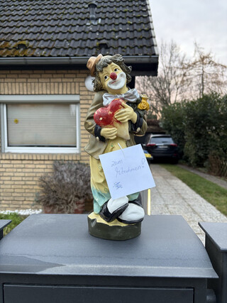 foto einer clown-figur die einen zettel tr&auml;gt: &bdquo;zum mitnehmen&ldquo;