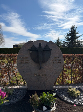 ein l&auml;chelnder jesus h&auml;ngt an einem grabstein und tr&auml;gt am rechten arm ein herz