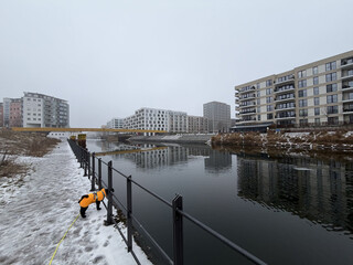 foto vom kanal am golda-meir-steg, es ist diesig, tr&uuml;b dun grau, im vordergrund steht unser pudel frida und schaut auf den kanal