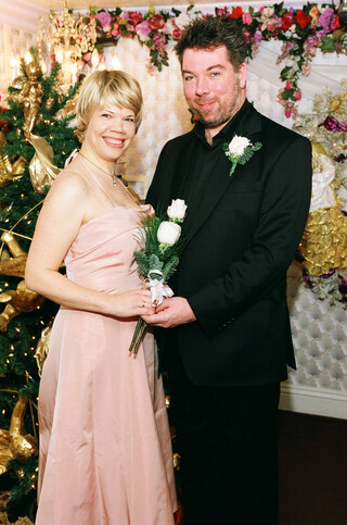 katia und ich in schick im kitsch, katia tr&auml;gt ein rosa kleid und felix einen schwarzen anzug, wir haben beide weisse-rosen-gestecke