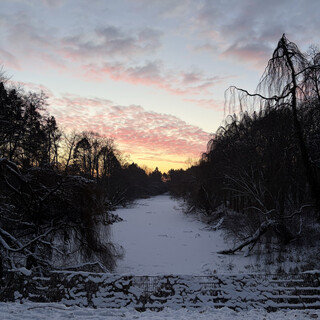 foto des zugefrorenen m&ouml;wensee beim morgenspaziergang. im hintergrund leuchtet der himmel orangeblau