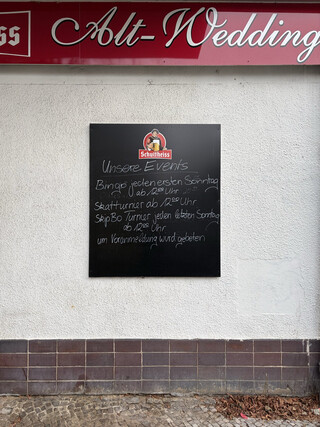 schild an der fassade der &bdquo;alt-wedding&ldquo; gastst&auml;tte. es wird um &bdquo;voranmeldung&ldquo; f&uuml;r &bdquo;Unser Events&ldquo; gebeten (Bingo, jeden ersten Sonntag, ab 12:00 Uhr, Skatturnier ab 12:00 Uhr, SkipBo Turnier jeden letzten Sonntag ab 12:00 Uhr)